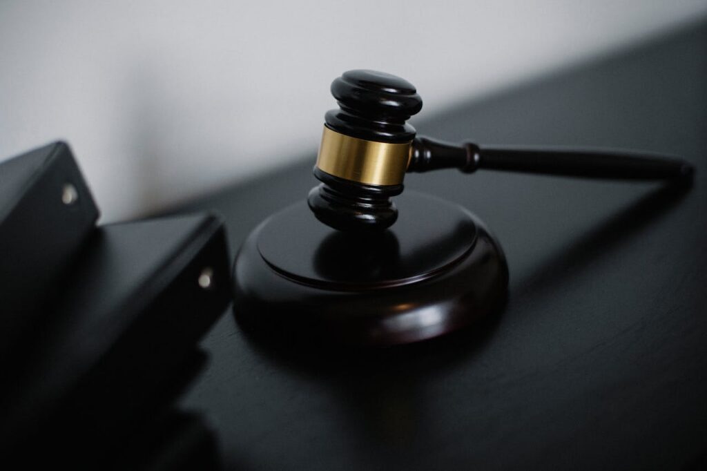 High angle of shiny wooden ceremonial mallet with golden detail placed on judge tale near documents folders